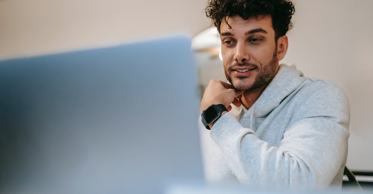 Ryanair: Wearable luggage, where's the limit? - Young friendly unshaven male remote worker in wearable tracker against netbook in light house room