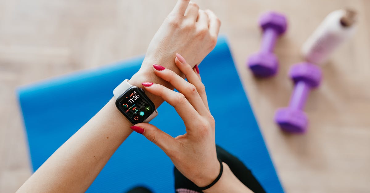 Ryanair: Wearable luggage, where's the limit? - Anonymous sportswoman checking smart watch and sitting on mat