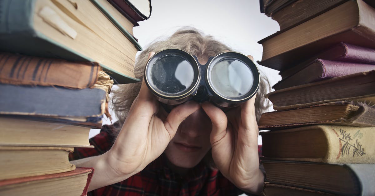 Safe to use binoculars in Dubai? - Man Using Binoculars in Between Stack of Books