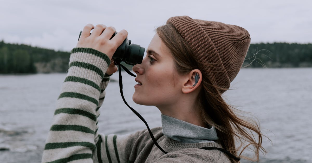 Safe to use binoculars in Dubai? - Woman in Knitted Cap and Sweater Using a Black Binoculars