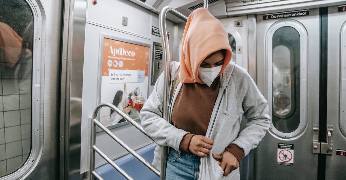 Safety concerns for traveling the Leh district - Muslim female in casual clothes medical mask and traditional headscarf in subway train