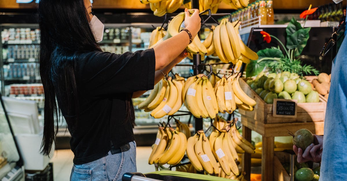 Safety considerations for solo female business traveller in Mexico - Woman With Face Mask Holding Yellow Banana Fruit