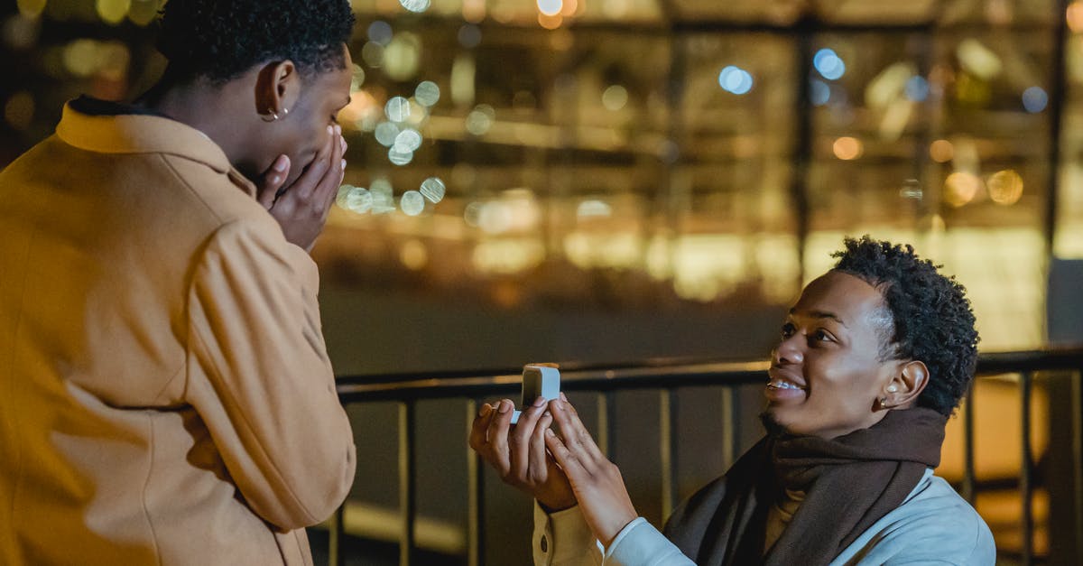 Same sex marriage in USA on visit/tourist visa? - Side view of African American knelling and doing proposal to amazed homosexual lover at night