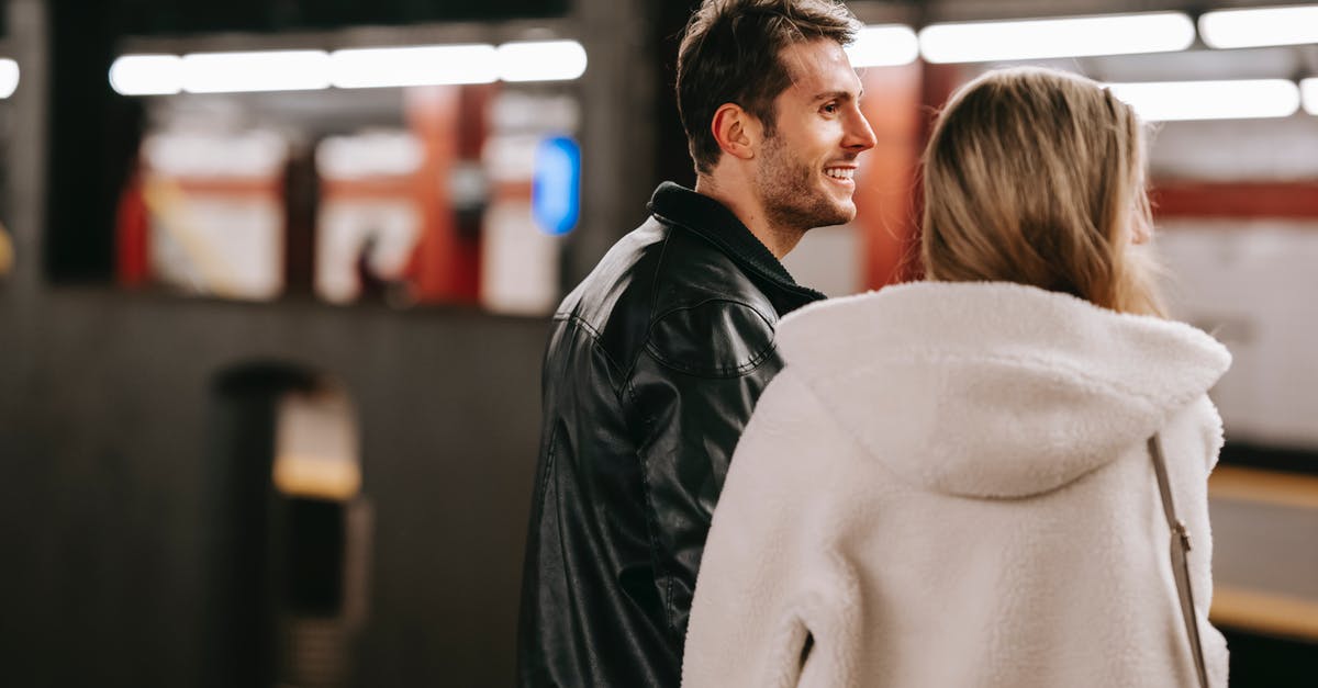 Saronno: what platform for MXP? [closed] - Smiling couple in casual clothes standing together in subway station with bright lights and looking away