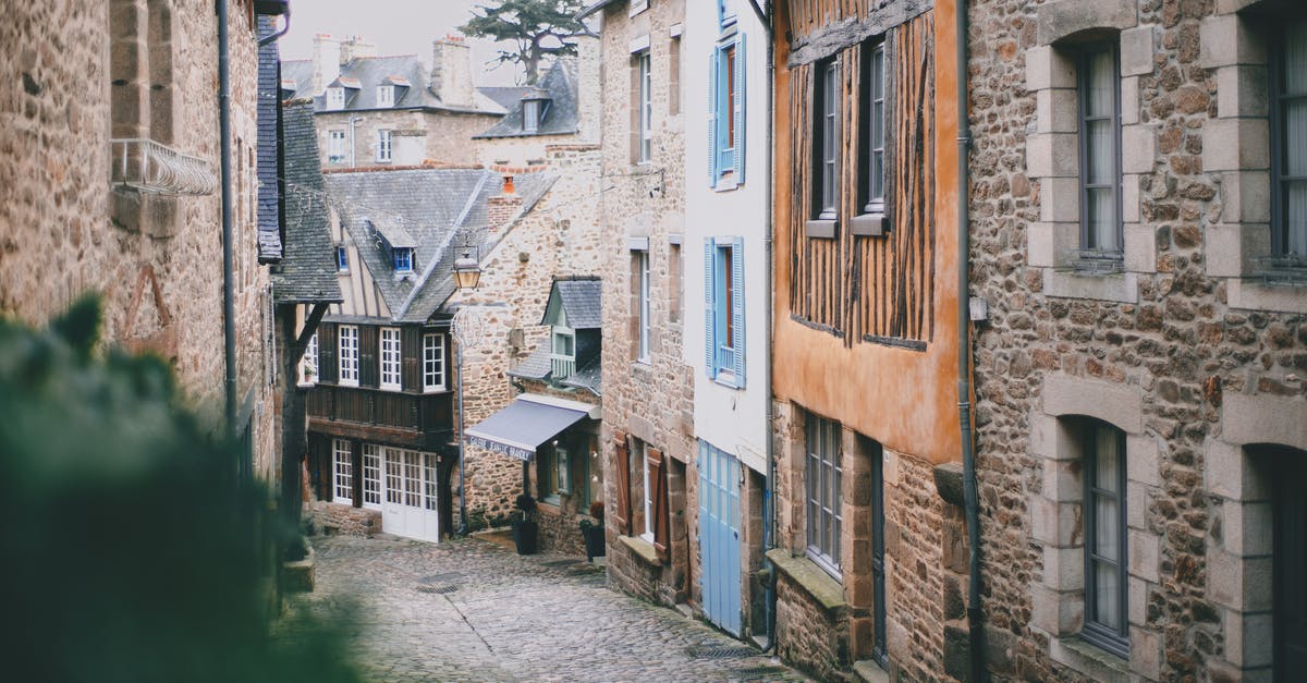 Schengen area visa: flying to Switzerland via Germany [duplicate] - Narrow cobblestone street with attached old brick and stone buildings in historic town on cloudy day