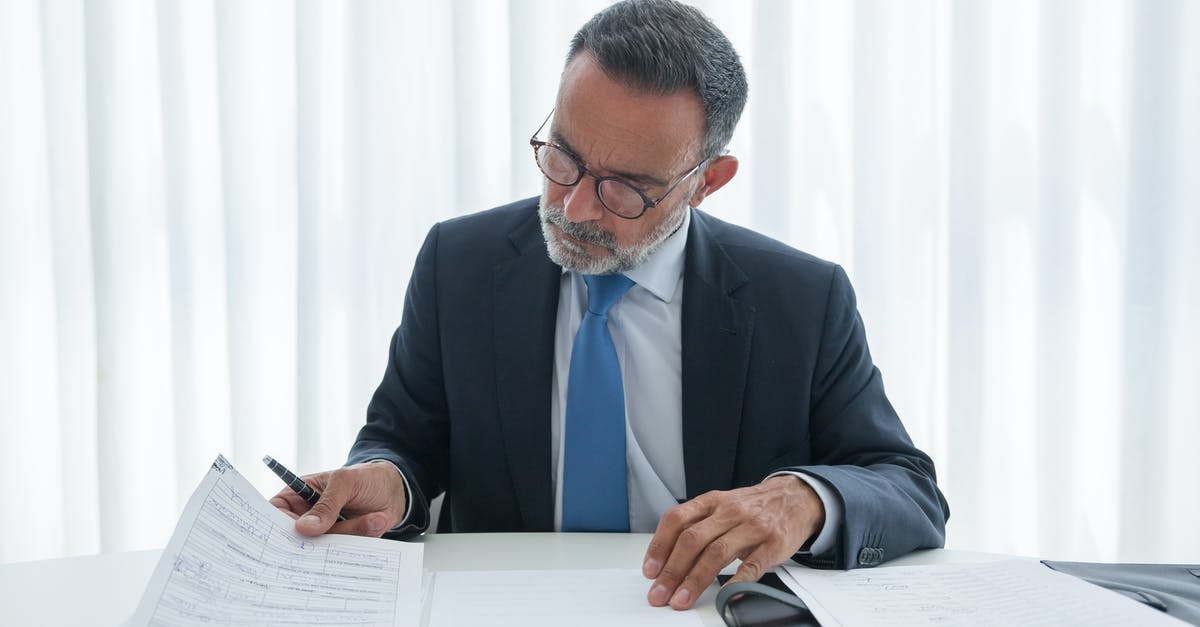 Schengen business visa for a recent graduate - Man in Black Suit Jacket Wearing Blue Necktie and Blue Necktie Writing on White Paper