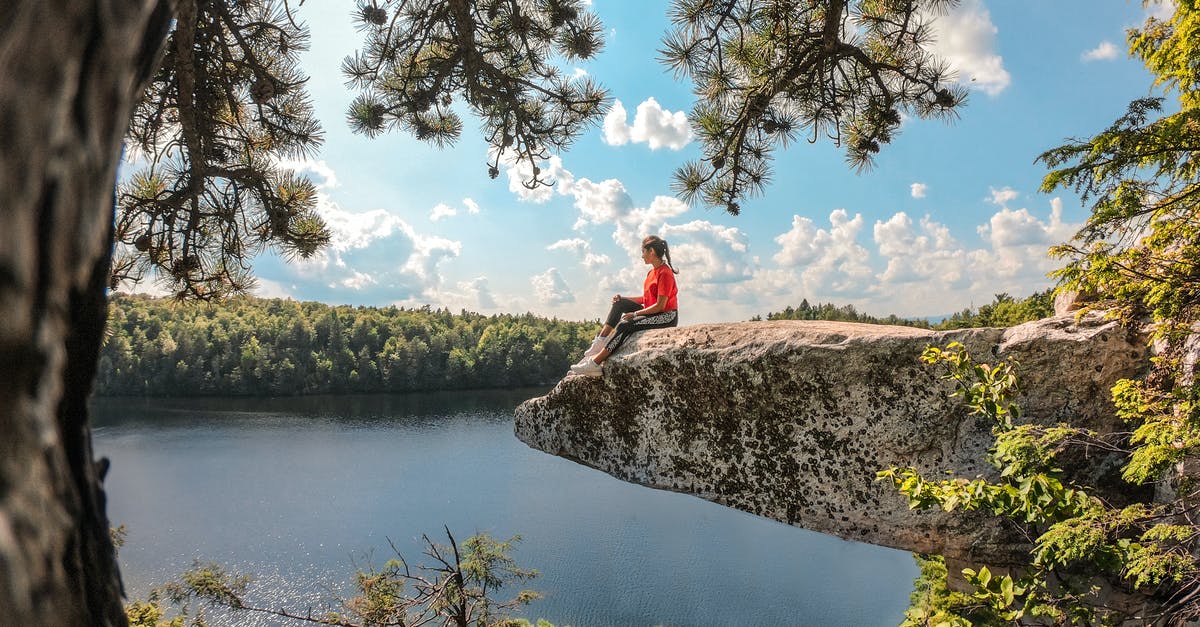 Schengen Tourist Visa - Girl Sitting on Rock Overhang Over Lake