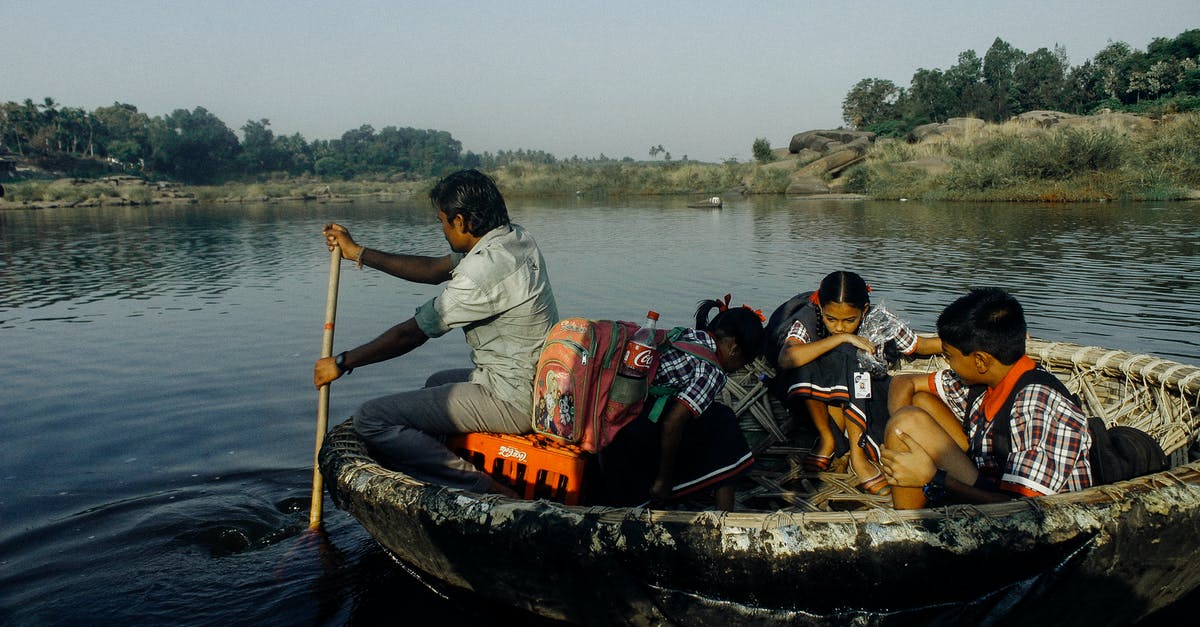 Schengen travel with minor Indian child born in Netherlands - Group of Indian man and schoolchildren with backpacks sitting in handmade boat while floating on water to school