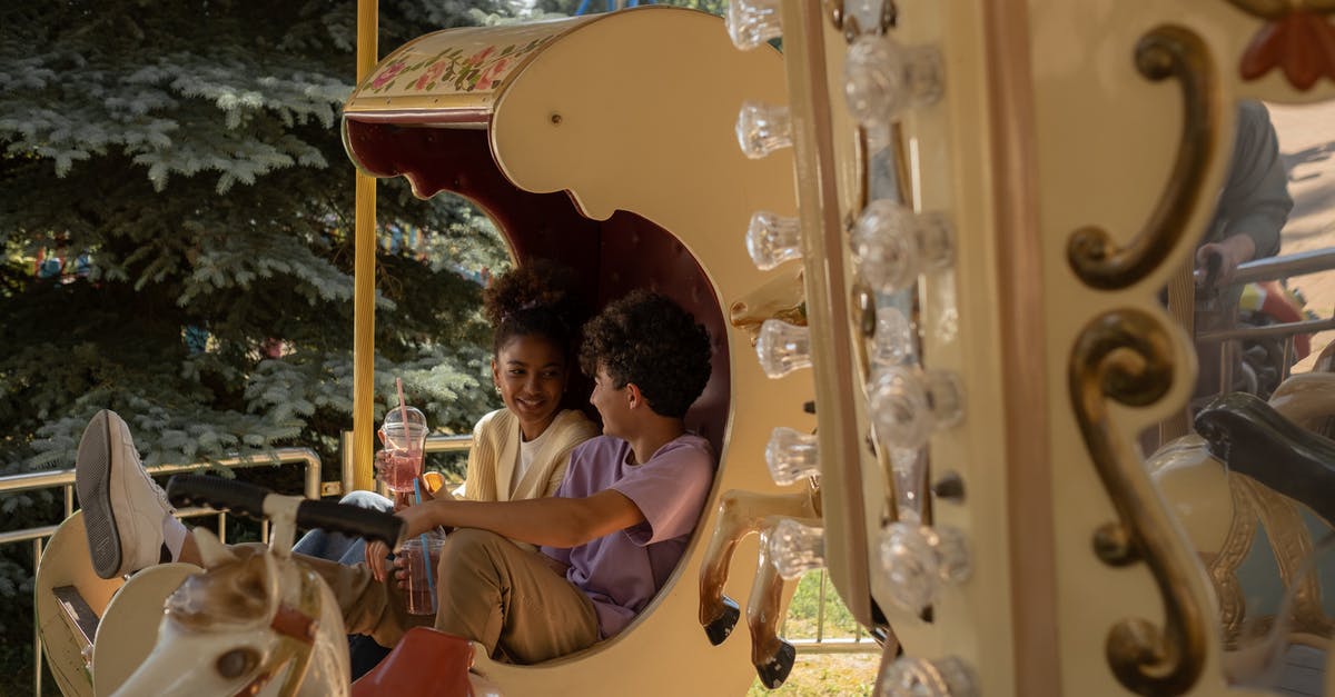 Schengen Visa - Date of Departure after first intended stay - Teenage couple sitting in carousel seat smiling and talking to each other