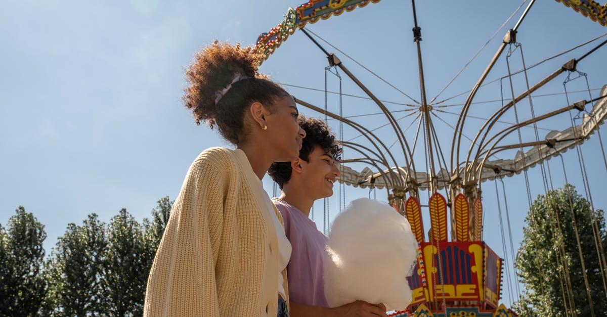 Schengen Visa - Date of Departure after first intended stay - Teenage couple walking by big carousel and boy holding cotton candy