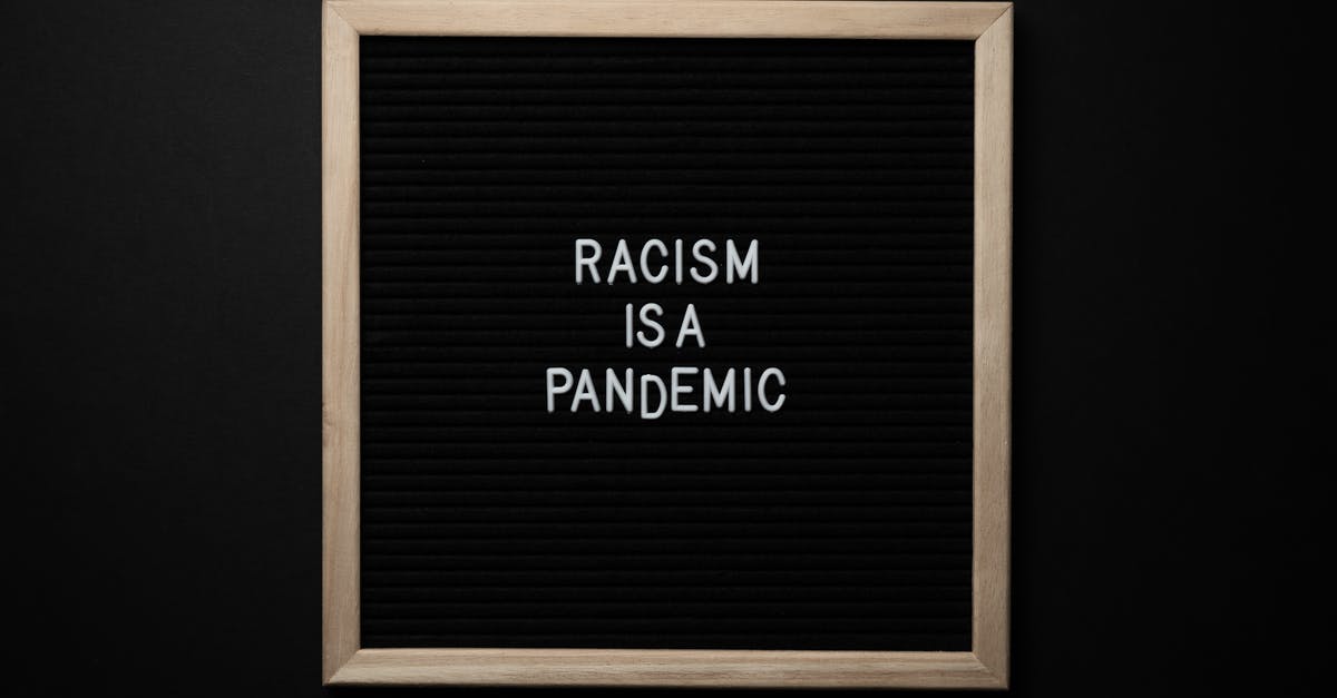 Schengen Visa . No response from the Consulate [closed] - Overhead view of slogan Racism Is Pandemic on black square signboard in light of lamps on black background