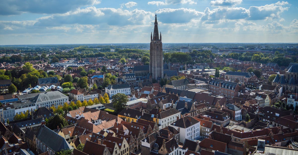 Schengen visa after a ban from Belgium - Spectacular drone view of Church of Our Lady and aged red roofed buildings in historical center of Bruges on sunny day