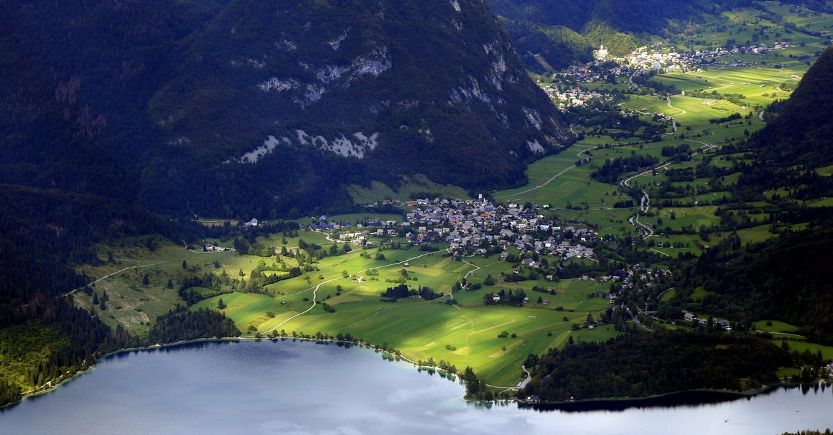 Schengen visa denied by Slovenia despite being the main destination - Aerial view settlements on grassy peaceful valley surrounded with green hills and calm river on sunny day