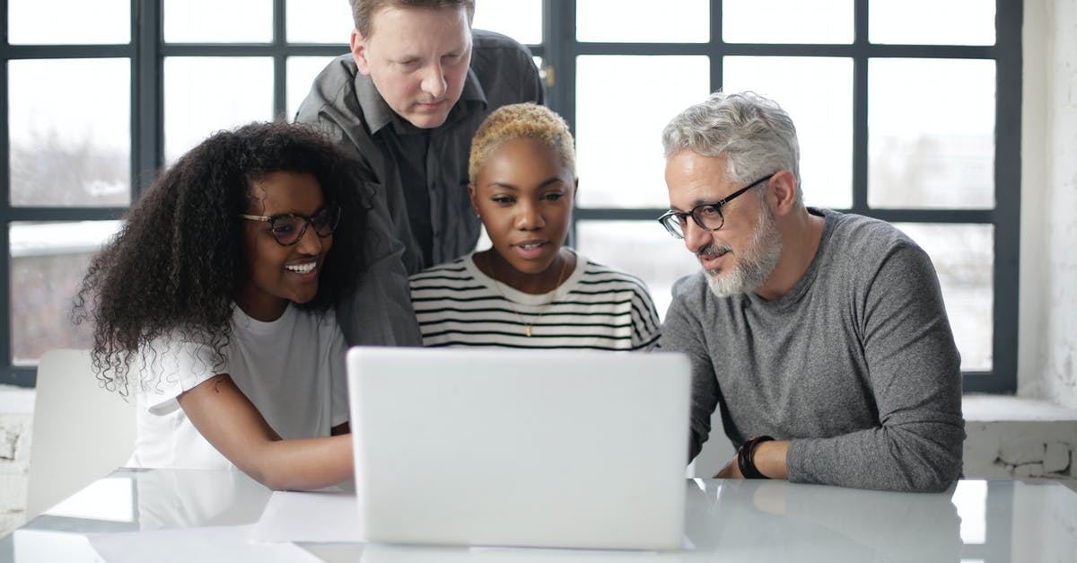 Schengen visa documents if the job is just 2 month old - Smiling women and men in casual wear sitting at table while working on project together in cozy office