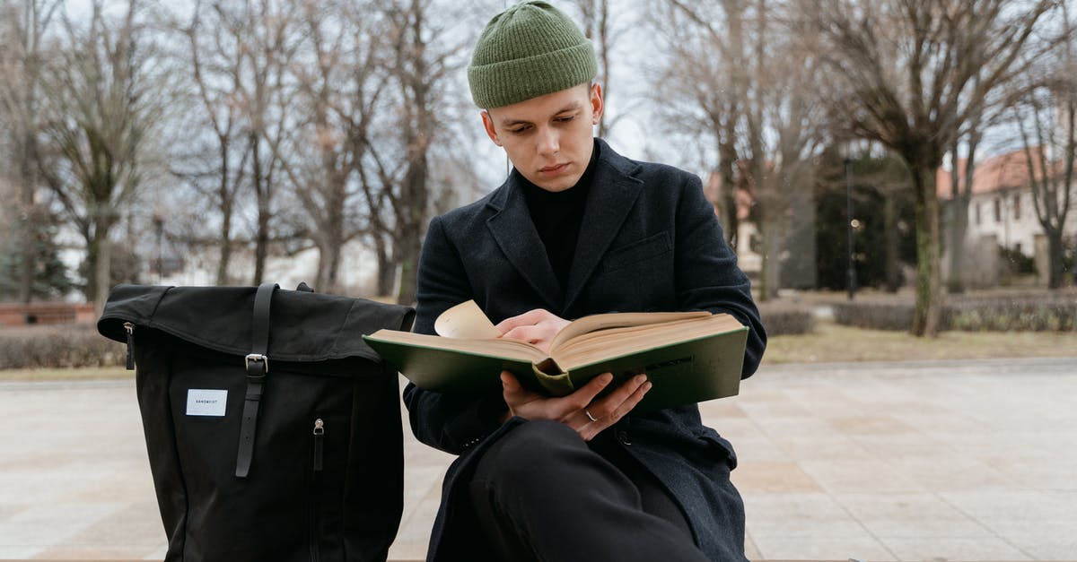 Schengen visa for international student in UK - A Man in Black Coat Sitting on a Bench Reading Book