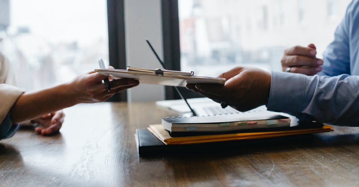 Schengen visa form: sponsor and applicant both - Crop anonymous ethnic woman passing clipboard to office worker with laptop during job interview