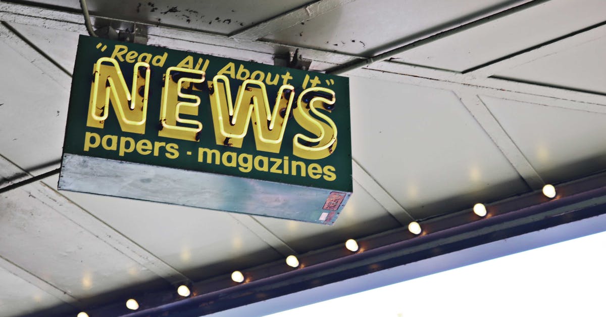 Schengen Visa from Seattle? - From below of illuminated signboard with news papers magazines inscriptions hanging on metal ceiling on street