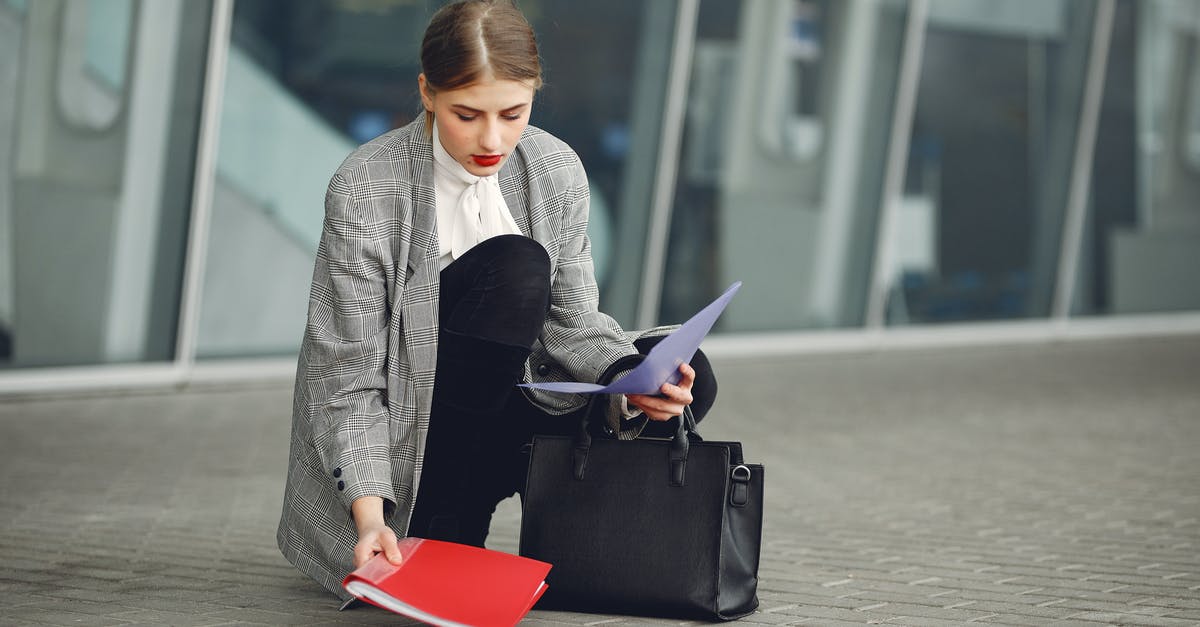 Schengen visa in almost full passport - Distracted female manager in trendy wear collecting scattered documents and passport from sidewalk into briefcase near glass wall of modern building