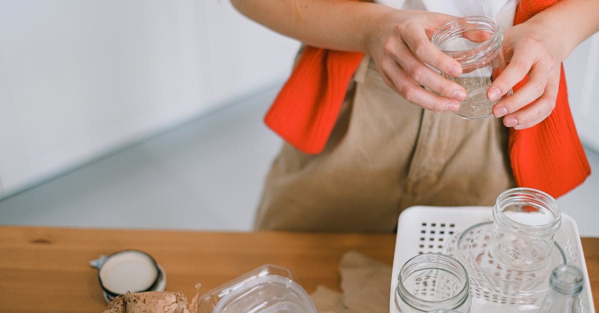 Schengen visa refusal and appeal process - Crop anonymous female in casual clothes standing with glass jar near table while sorting out paper plastic and glass rubbish for recycling