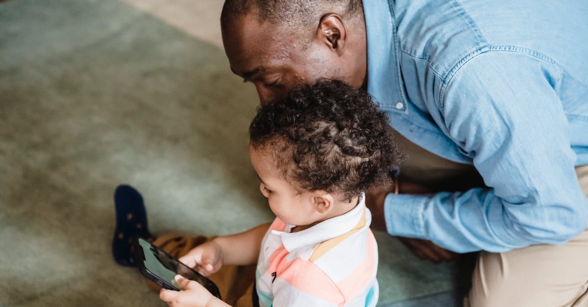 Schengen visa sponsored by my father - A Child using a Smartphone next to his Father