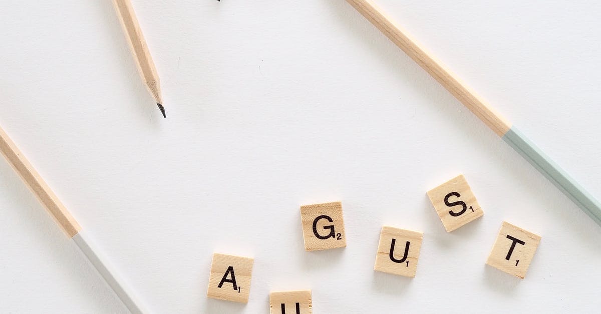 Schengen Visa Sponsorship Letter Format - Flat lay of small wooden cubes with letters saying August arranged on white background with scattered pencils on table in room