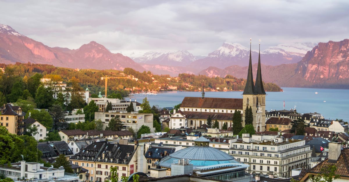 Schengen visa to travel from Germany to Switzerland - Majestic scenery of medieval city with Gothic cathedral in Alps on green seashore