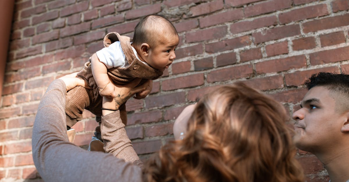 Schengen visitor visa for parents - Woman in Brown Long Sleeve Shirt Carrying Baby in White Shirt