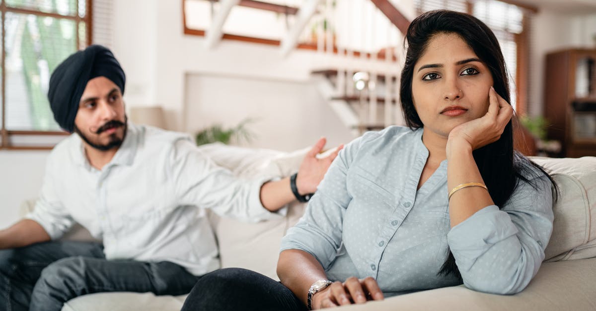 Seat issue confirmed or cancelled on Indian Railways? - Young bearded Sikh man in casual wear and turban arguing with sad wife sitting on sofa