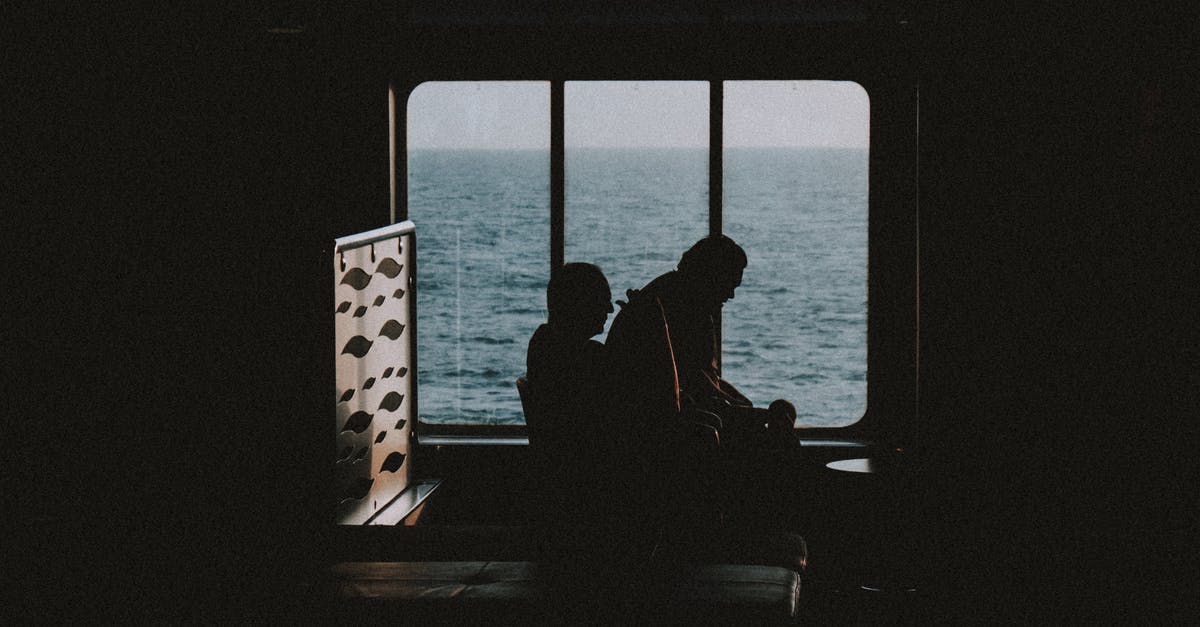 Seat pitch / leg room on EVA Air SEA - TPE - KUL? - Silhouette of unrecognizable tourists sitting next to window and relaxing in dark room on passenger ship