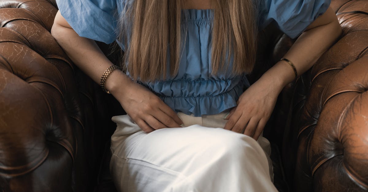 Seat pitch / leg room on EVA Air SEA - TPE - KUL? - Crop unrecognizable young female in casual clothes resting in comfortable leather brown armchair with legs crossed and leaning on elbows