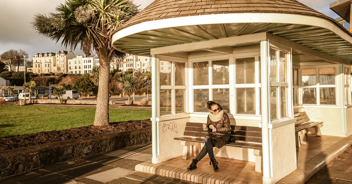 Second most photographed building in the southern hemisphere - why? - Full body young female in casual warm wear sitting on bench in white small summerhouse located in green district of southern town