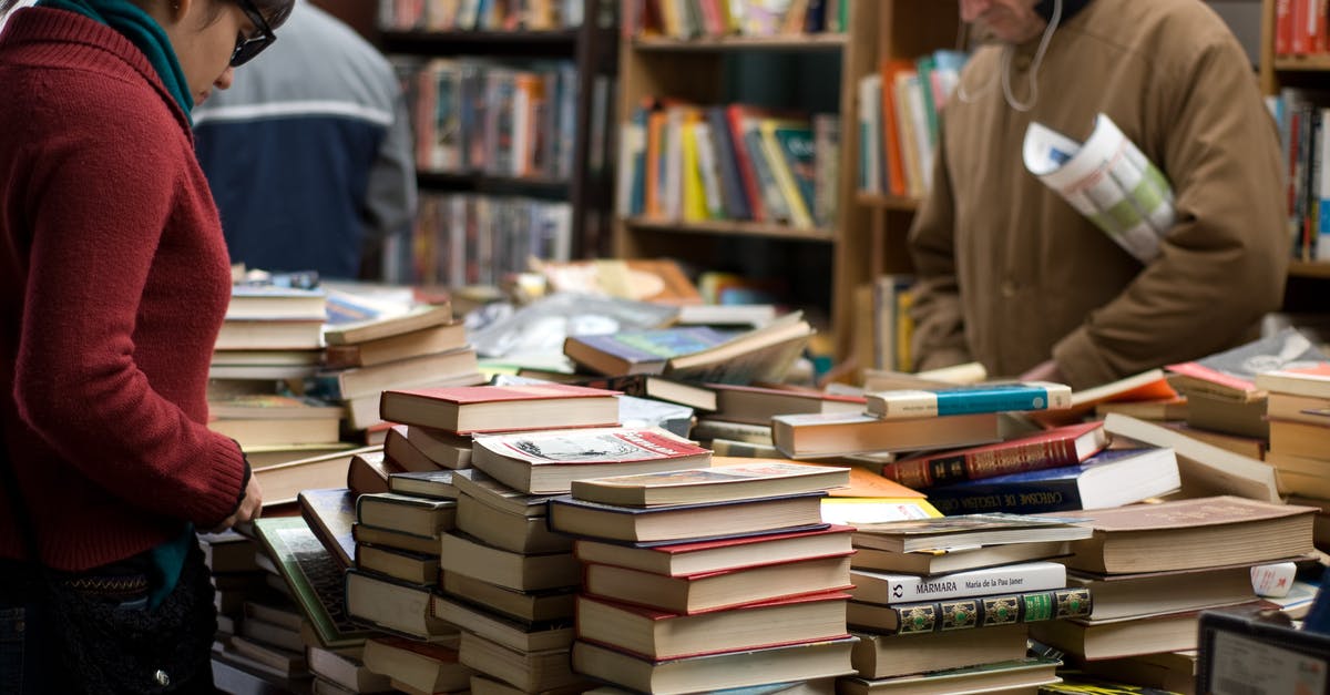 Secondhand book market or area in Beijing? - Woman and Man Standing Beside Piles of Books