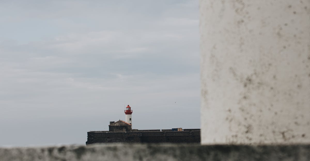 Security situation along I-75 on Florida's Gulf Coast - Distant lighthouse tower built on stony embankment seen from behind of concrete structure against overcast sky