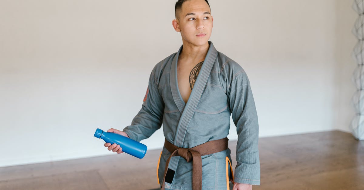 See-through kimono in the Vatican? - Man in Gray Kimono and Brown Belt Holding Blue Tumbler