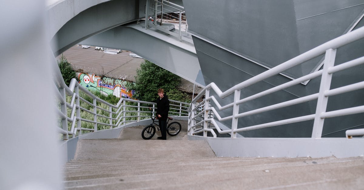 Sending my bike cover from airport A to airport B // pick-up 9 days later - Man in Red Jacket and Black Pants Walking on White Concrete Stairs