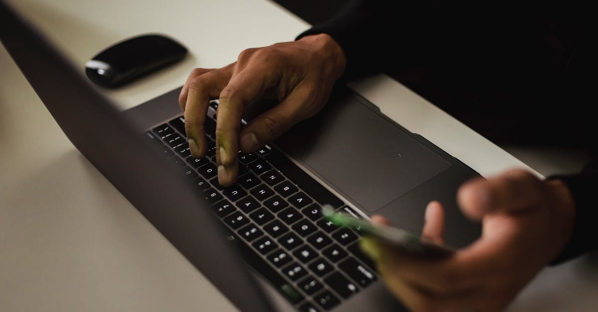 Sending my passport as part of my Canada Visa Application - Crop faceless man typing on laptop and using smartphone