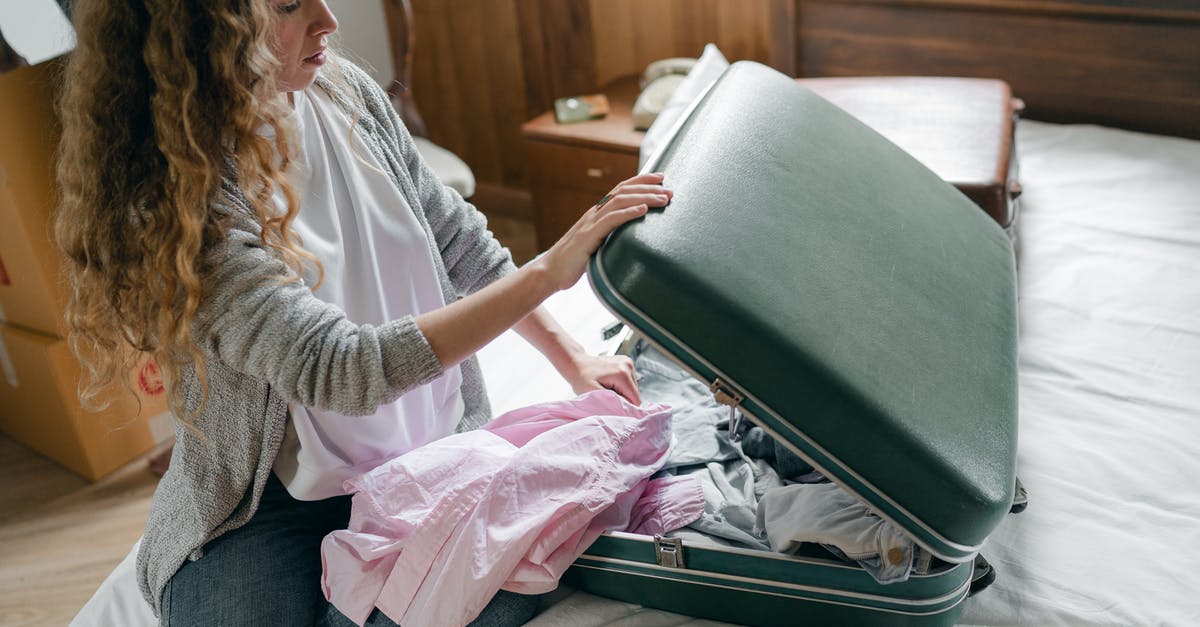 Services to help disabled travelers when travelling, eg with accommodation in Canary Islands and travel from Russia - Focus woman packing suitcase on bed Services to help disabled travelers when travelling, eg with accommodation in Canary Islands and travel from Russia - Focus woman packing suitcase on bed