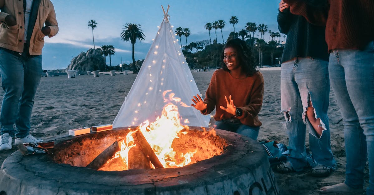 Setting up a tent on a beach in Greece - Woman Warming Her Hands in Front of the Fire Pit