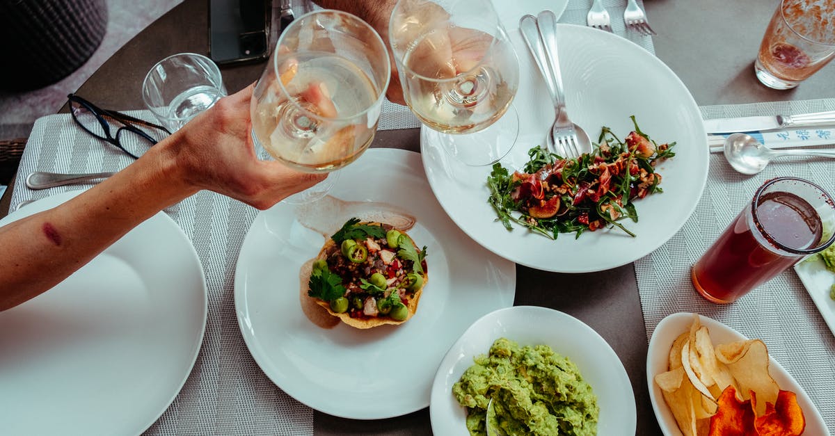 Shipping Wine from Italy to the UK [closed] - Two Unrecognizable Hand Holding Glasses of Wine Above Plates of Colourful Salads