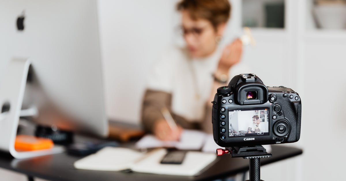 Short Connection - Unrecognizable blurred lady working at table in modern office against photo camera placed on tripod