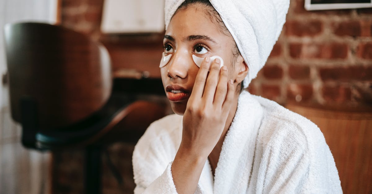 Should I apply for NIF before renewing my Passport? - Young African American female with towel on head applying eye patches on face while looking away