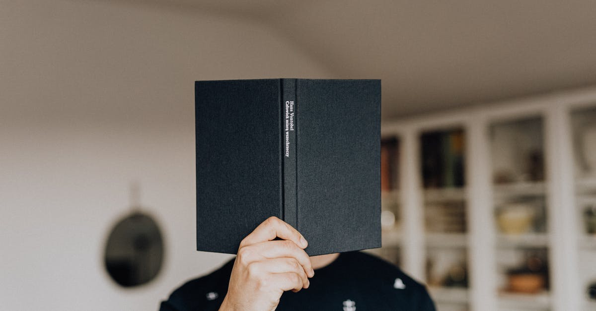 Should I book in advance cooking course in Thailand? - Faceless male holding opened black book in hand covering face while standing in middle of light room