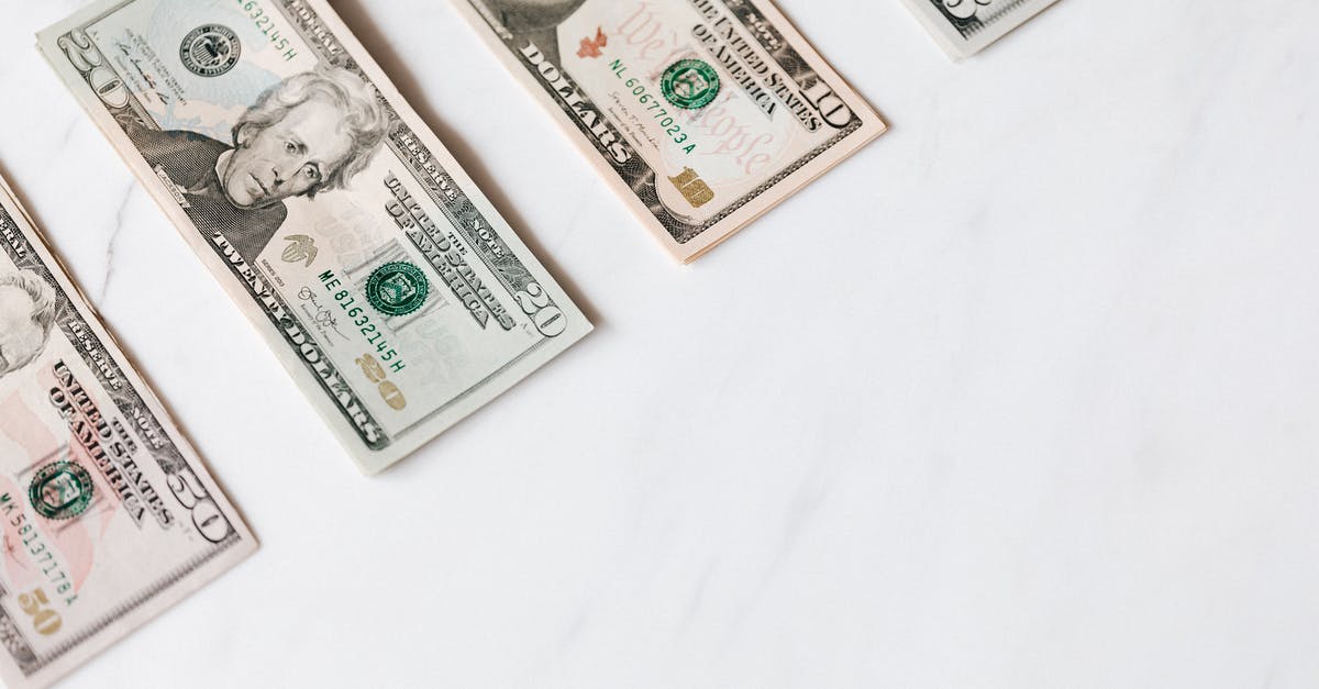 Should I deposit money back into my account when waiting for a visa - Set of various dollar banknotes on white table Should I deposit money back into my account when waiting for a visa - Set of various dollar banknotes on white table
