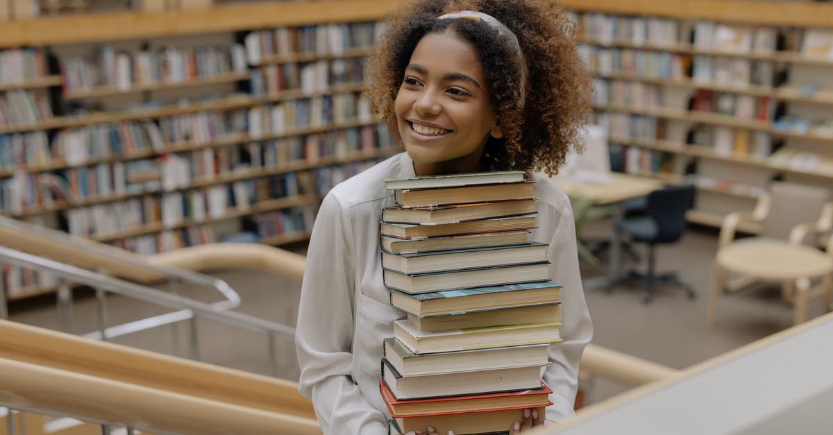 Should I put books in carry-on or checked luggage? - Photo Of Woman Carrying Stack Of Books 