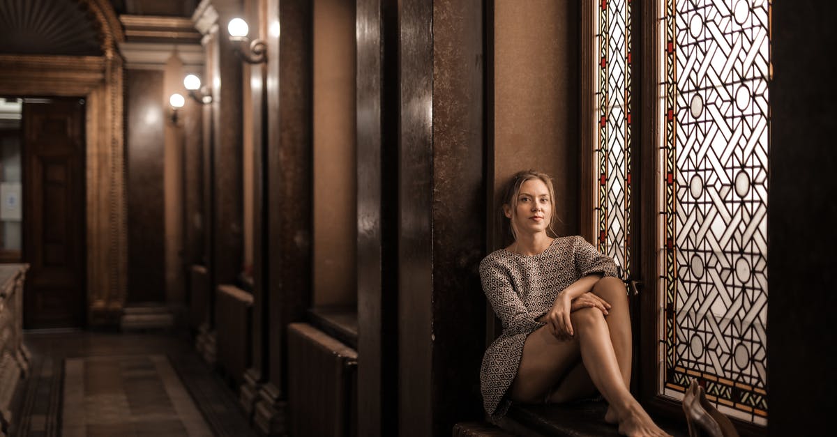 Should I travel to Morocco alone as a young female? - Blonde barefoot female sitting by painted window in dark lobby with Gothic interior