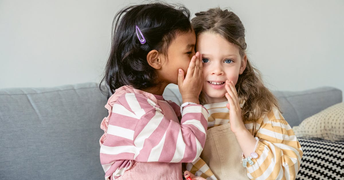 Silent / quiet luggage, trolley, on wheels [closed] - Ethnic girl sitting on sofa close to smiling best friend and whispering secrets on ear