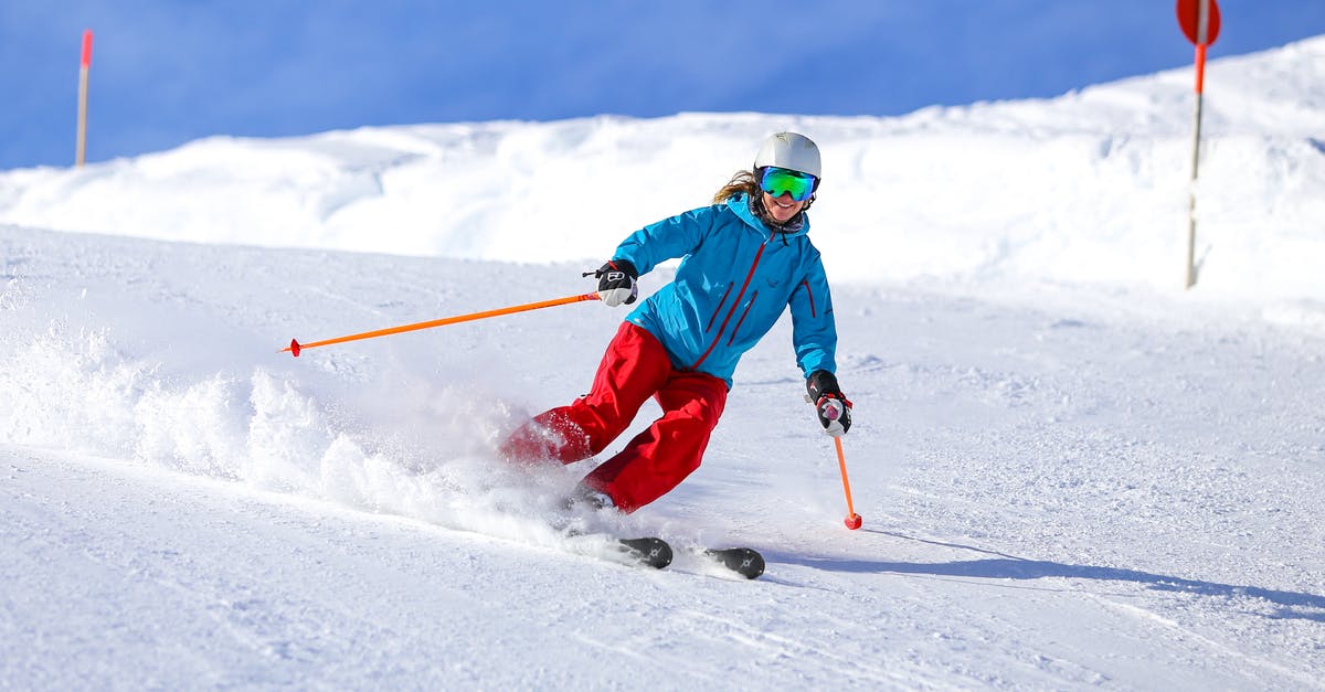 Skiing near Bangalore? - Man in Green Jacket and Blue Pants Riding on Ski Blades on Snow Covered Ground during