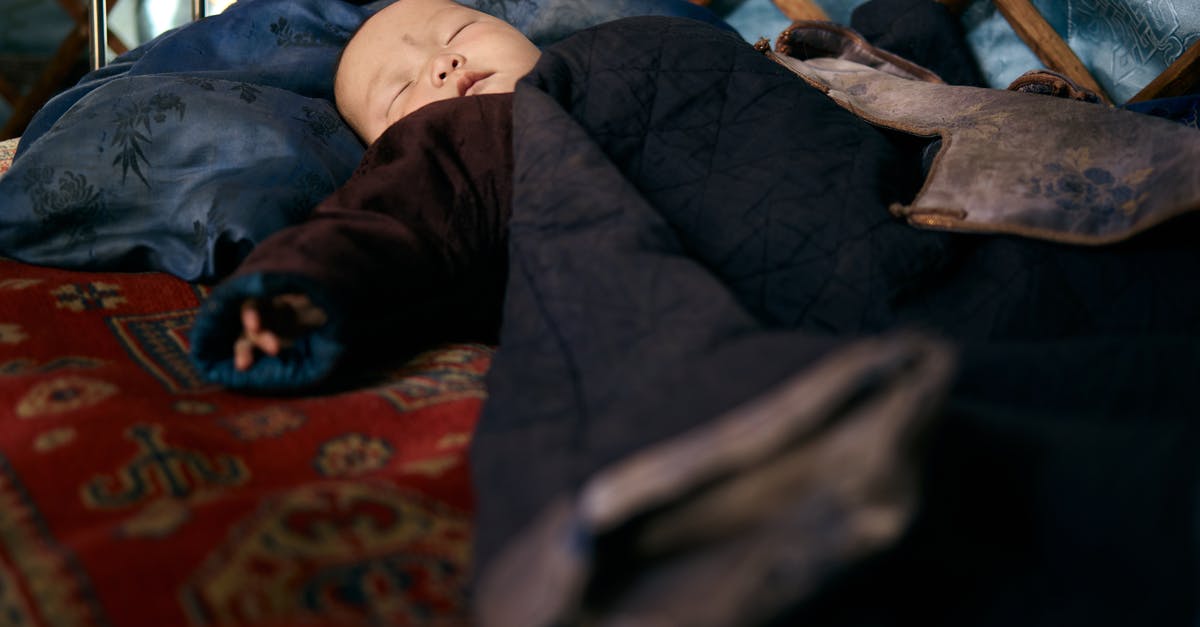 Sleeping overnight at Reagan National (DCA) airport - Full length Asian infant lying on carpet while sleeping in warm national clothes under blanket