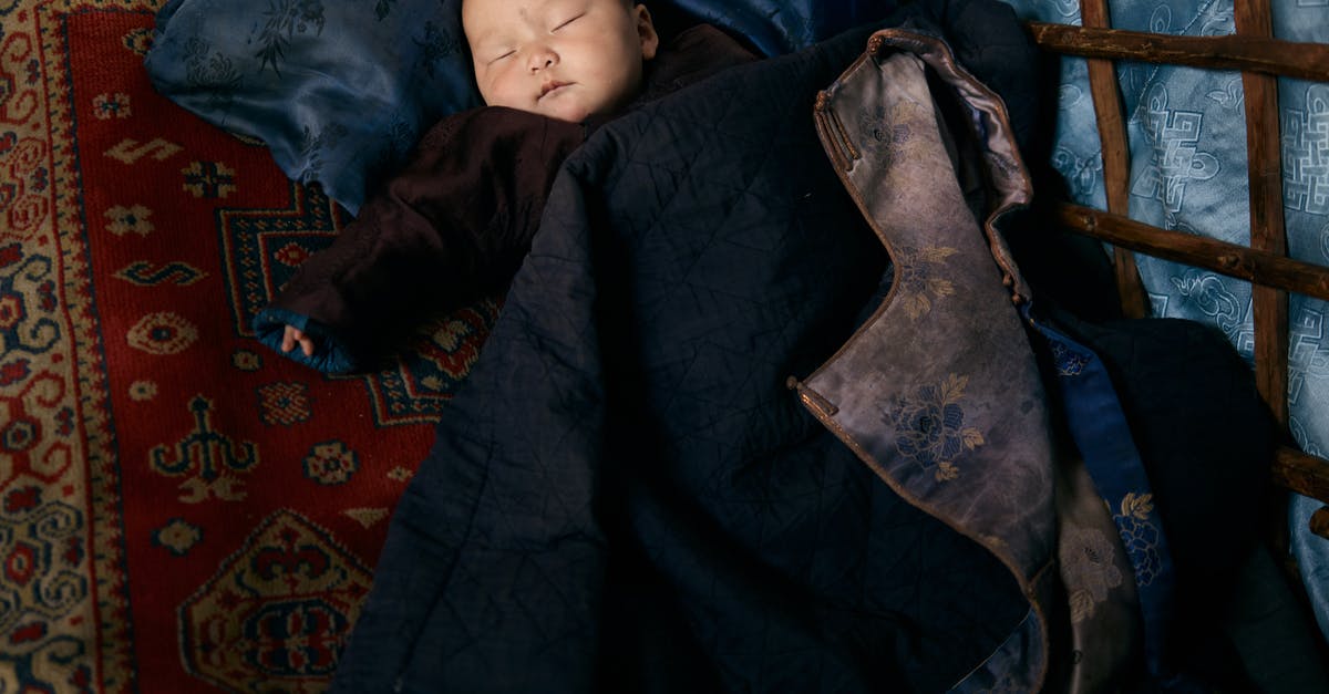Sleeping overnight at Reagan National (DCA) airport - From above of full length sleeping Asian infant in warm clothes lying on carpet under adult man jacket with floral backing