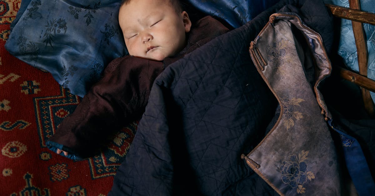 Sleeping overnight at Reagan National (DCA) airport - Top view of small ethnic baby in warm clothes sleeping on carpet and pillow under jacket with floral backing